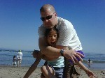 A man hugging his daughter on a beach